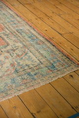 Distressed Oushak rug corner, showing faded red, blue patterns, and visible foundation.