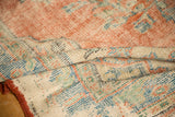 Distressed Oushak rug texture showing worn cherry red pile, woven reverse, and secured edge.