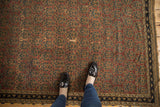 Antique Afshar rug's aubergine field with allover navy and sand botehs, showcasing authentic surface wear.