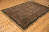 Allover boteh pattern across the antique Afshar rug's aubergine field and dark navy blue border details.
