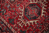 Vintage Karaja rug section with cherry red field, geometric vinery, and navy hook-and-latch motif.