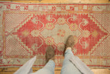 Textured vintage distressed Oushak runner with bright red and pale beige floral patterns, underfoot.