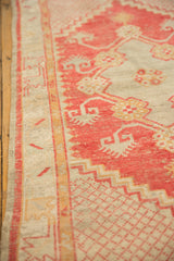 Close-up of the vintage Oushak runner's distressed texture and faded red geometric patterns.