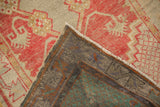 Folded corner of vintage distressed Oushak rug, showing even wear, hand-knotted reverse, and fringe.