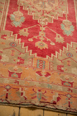 Distressed Oushak rug detail featuring faded raspberry red, geometric lotus elements, and tangerine border.