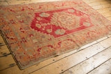 Distressed Oushak rug corner, showing geometric border in faded raspberry and pale tangerine.