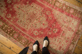 Faded raspberry red and pale bronze stepped geometric pattern on a distressed Oushak rug.