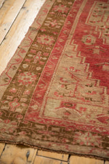 Faded raspberry red and pale bronze geometric border of a distressed Oushak rug.