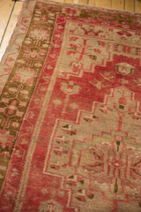 Distressed Oushak rug texture with faded raspberry red and pale bronze geometric patterns.