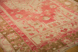 Faded raspberry and pale bronze geometric border detail on a distressed Oushak rug.