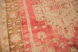 Close-up of distressed Oushak rug's low pile with faded raspberry red and bronze motifs.