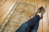 Distressed vintage Oushak rug runner with gold and ivory texture, showing diamond medallion.