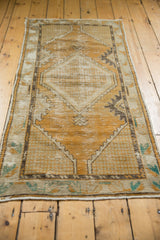 Distressed texture of a vintage Oushak rug's dusty gold field, with ivory and aqua border.