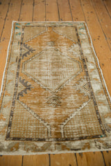 Fringed end of vintage distressed Oushak runner, showcasing worn texture in gold and ivory.