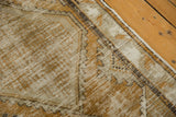 Detail of vintage distressed Oushak rug showing worn pile, dusty gold, ivory, and dark tones.