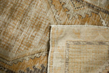 Distressed vintage Oushak rug pile in dusty gold and ivory, showing hand-knotted foundation.