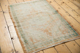 Distressed Oushak rug corner with faded apricot, ivory, turquoise border and visible wear.