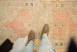 Vintage Distressed Oushak rug, blush, rose, and ivory, with faded scalloped medallions.
