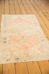 Distressed vintage Oushak rug featuring soft blush, ivory, and silver tones with visible foundation.
