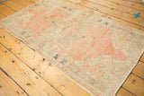 Secured side of the distressed vintage Oushak rug with blush and ivory worn pile.