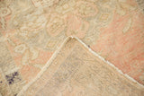Distressed Oushak rug corner showing worn blush and ivory pile, plus hand-knotted foundation.
