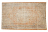 Distressed Oushak rug with faded roundel medallion, continuous vinery, apricot, ivory tones.