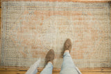 Distressed Oushak rug showcasing worn pile and rhythmic border in apricot and ivory.