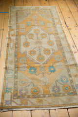 Distressed Oushak pile texture showing even wear, with saffron and aqua blue florals.