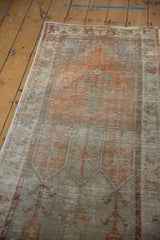 Vintage Distressed Oushak runner detail: faded orange, seafoam green plant motif, visible wear.