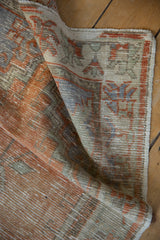 Distressed Oushak pile revealing foundation, with faded orange, silver, and seafoam green.