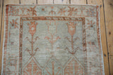Distressed texture of worn orange and seafoam green pile with foundation showing through.