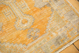 Close-up of gold orange and ivory distressed Oushak rug with faint foundation showing.