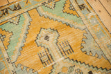 Distressed gold orange, mint green, and pale blue geometric detail on a vintage Oushak rug.