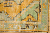 Distressed Oushak runner edge, gold orange, mint, pale blue geometric steps, visible pile wear.