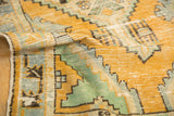 Vintage Oushak rug pile texture with worn gold orange, mint green, and pale blue.