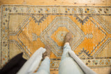 Distressed vintage Oushak runner with tangerine orange field, silver diamond medallion, and vine motifs.