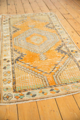 Distressed tangerine orange Oushak rug field with visible wear and meandering vine palmette border.