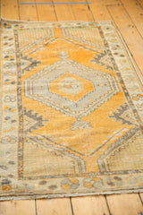 Distressed Oushak rug corner showcasing halved palmette medallions, vine border, and knot head wear.