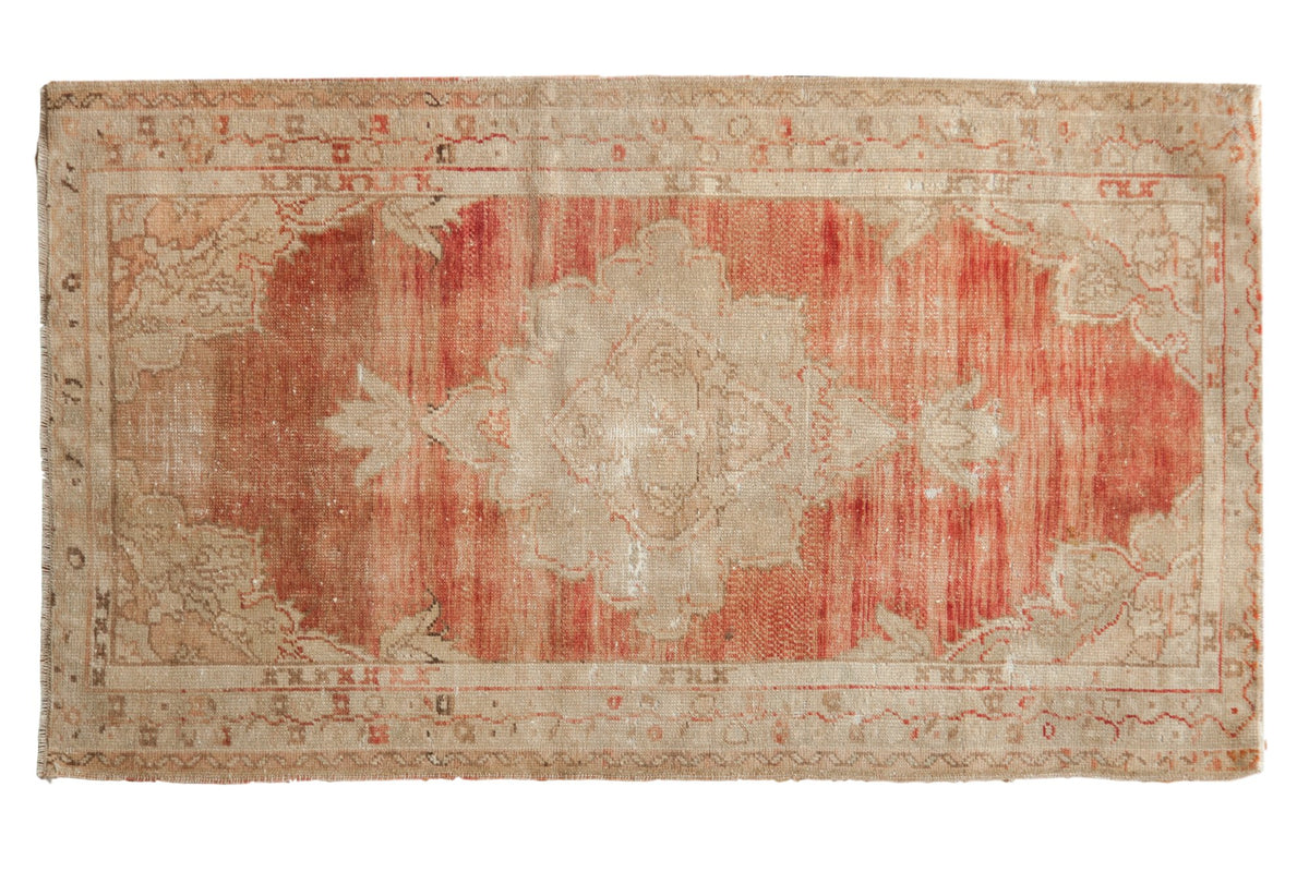 Vintage distressed Oushak rug with a scalloped ivory medallion on a heavily abrashed and striated soft red field.