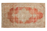 Vintage distressed Oushak rug with a scalloped ivory medallion on a heavily abrashed and striated soft red field.