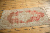 High angle view of a vintage Oushak rug showing its faded red and ivory central medallion.