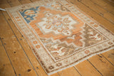 Vintage Oushak rug corner showing starburst border, worn pile, and fringe.