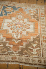 Visible wear on a distressed Oushak rug corner, with stepped motifs and faded copper, blue.