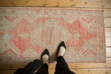 Distressed vintage Oushak runner, geometric blush pink and beige patterns with visible even wear.