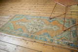 Distressed Oushak runner, diamond medallion, with warm pale gold, mint green, and sky blue.