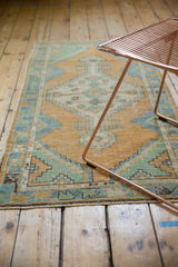 Distressed Oushak rug pile revealing pale gold, mint, and sky blue tones with even wear.