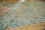 Distressed vintage Oushak carpet with mostly even wear in muted beige and blue-green tones.