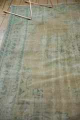 Distressed Oushak vintage carpet with worn beige pile and hints of blue-green motifs.