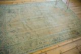 Vintage distressed Oushak rug border with faded beige pile and muted blue leaf patterns.
