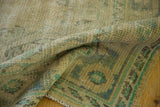 Distressed Oushak pile with even wear, soft beige, and faded blue-green leaf motifs.